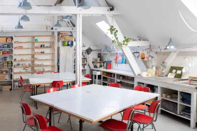 Atelierraum mit Tischen, Stühlen und gefüllte Regalen